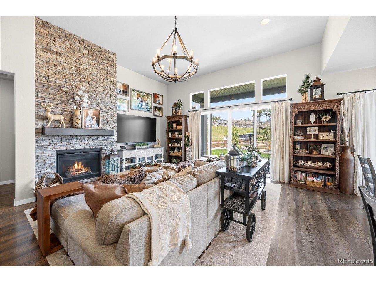 Image 4: Spacious living area featuring a stone-clad fireplace with a dark wood mantel, high vaulted ceilings, and dark wood-finish flooring Image 4: Spacious living area featuring a stone-clad fireplace with a dark wood mantel, high vaulted ceilings, and dark wood-finish flooring