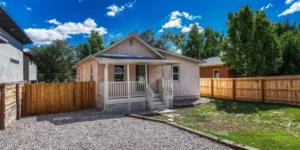 Image 2: Stucco exterior with a covered porch, white railing, and a gravel driveway