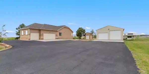 Image 3: Side entry of home with asphalt driveway, 3-car attached garage, small shed and large shop with RV garage door. Image 3: Side entry of home with asphalt driveway, 3-car attached garage, small shed and large shop with RV garage door.