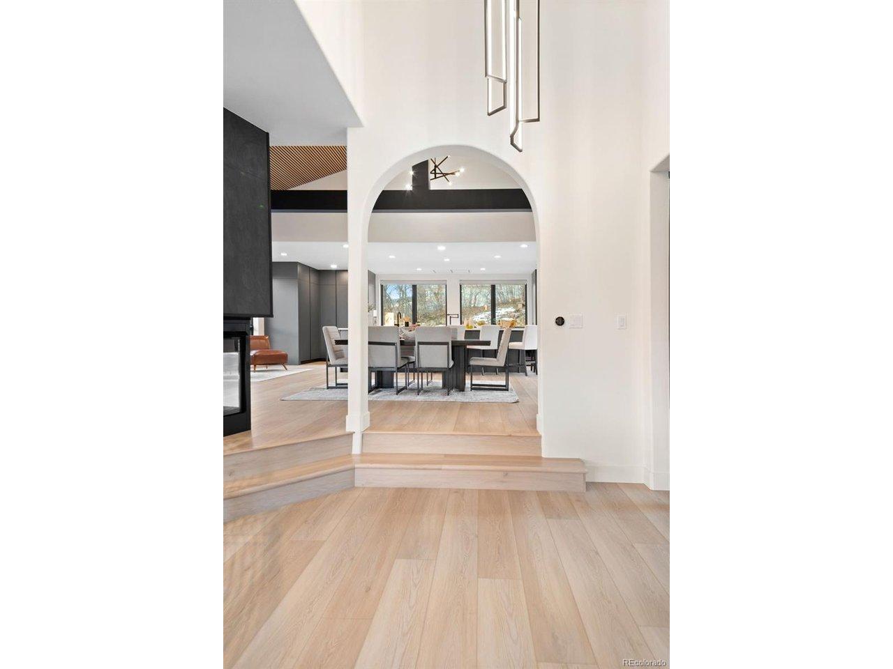 Image 3: Grand entry hall revealing the home's open layout - living room to the left, kitchen straight ahead, and the Red Rocks visible through every window
