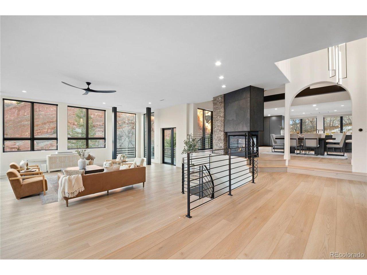 Image 4: Open concept main living area with fireplace, hardwood floors, and walls of windows framing the formations