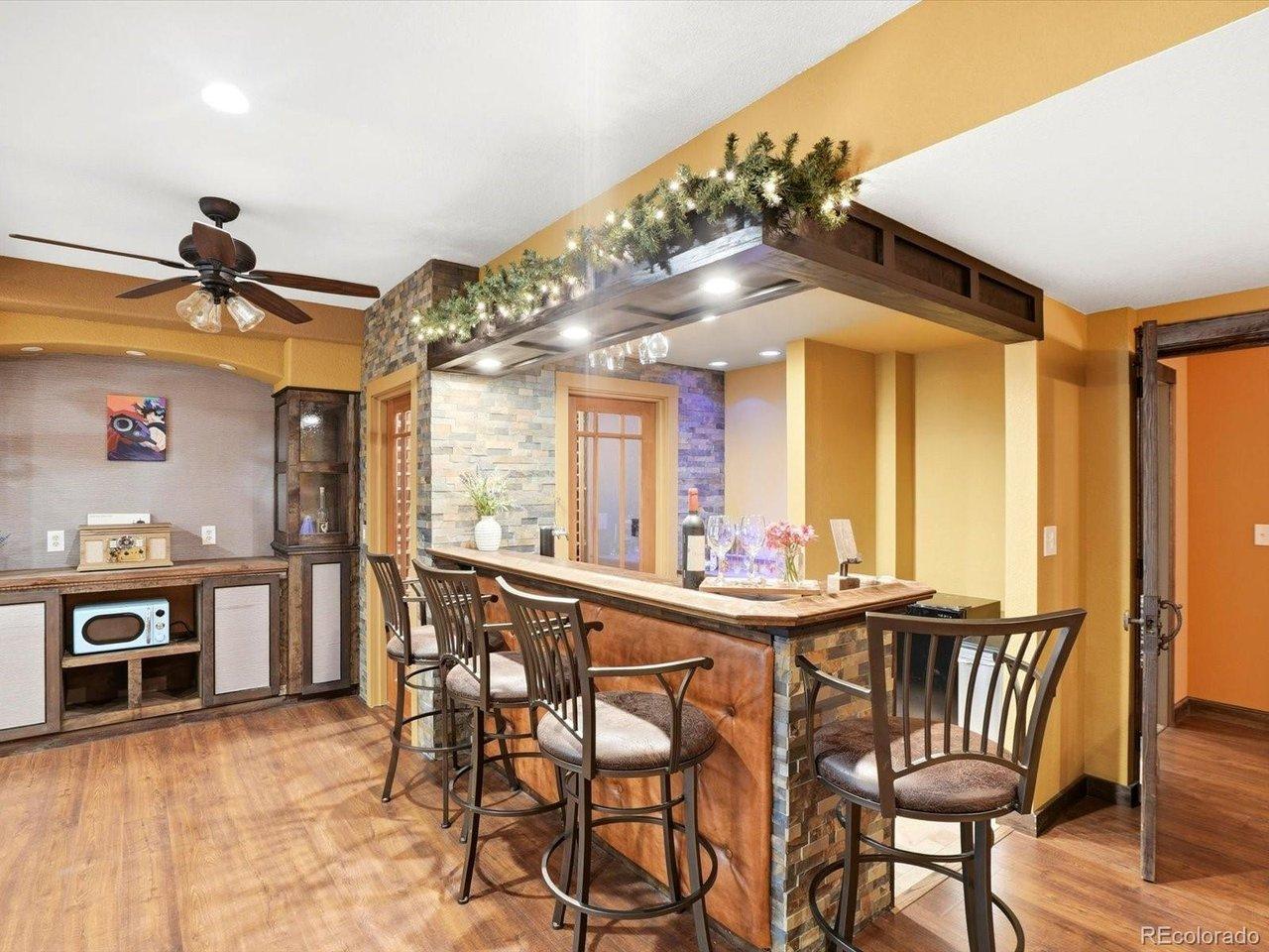 Image 2: Custom built-in display shelves, wet bar with sink, and wine cellar adjacent to media room