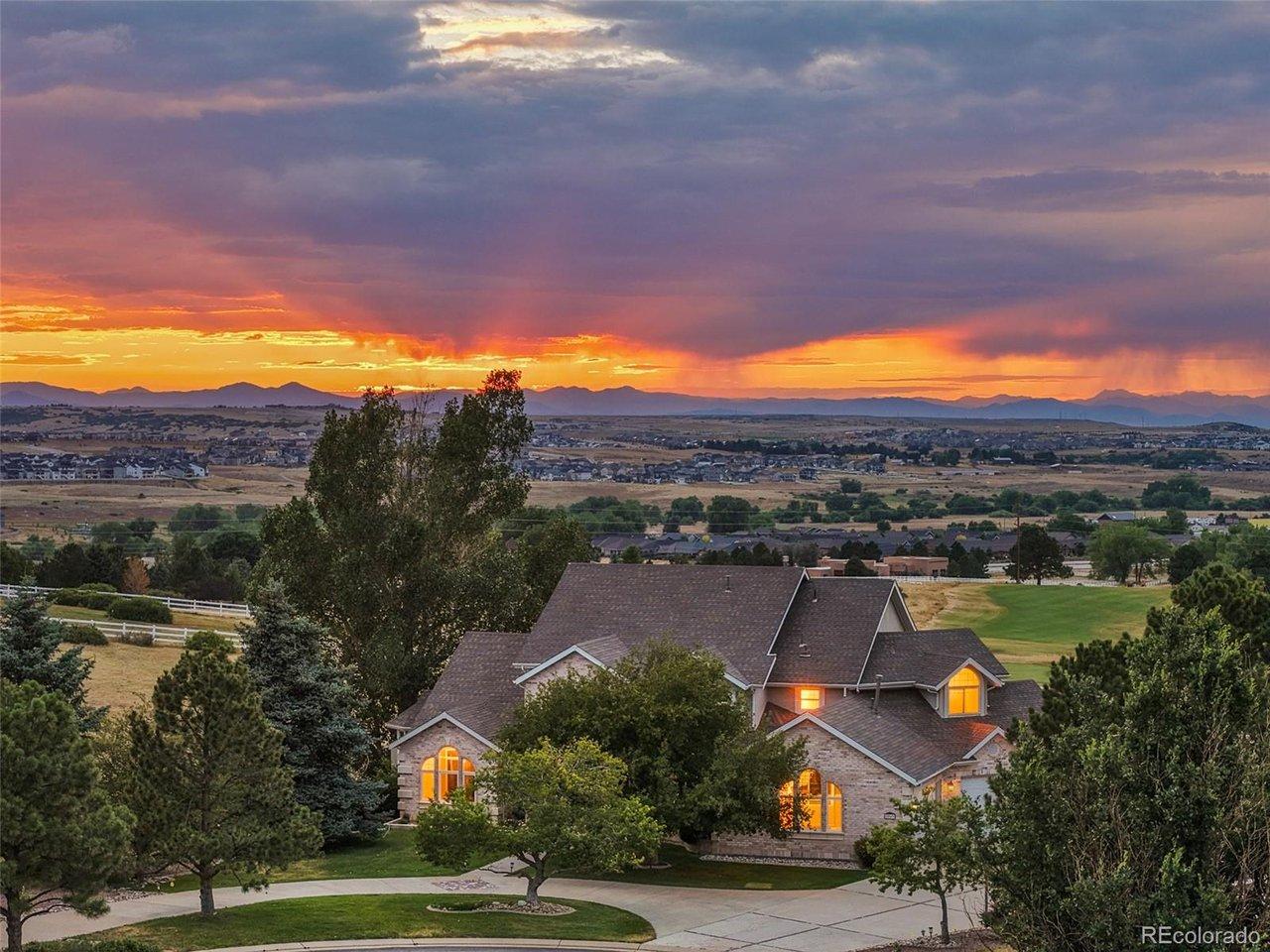 Image 2: An elevated twilight view captures the home's impressive arrival, mature landscaping and sweeping Front Range sunset backdrop.
