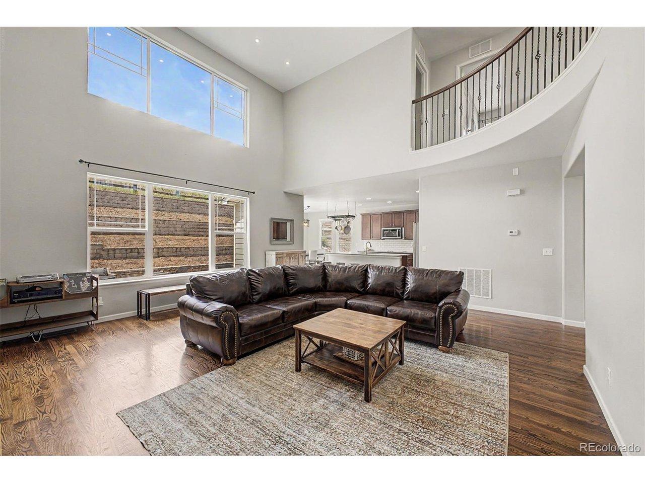 Image 2: Dramatic Two-Story Family Room with Expansive Windows & Open Loft Above