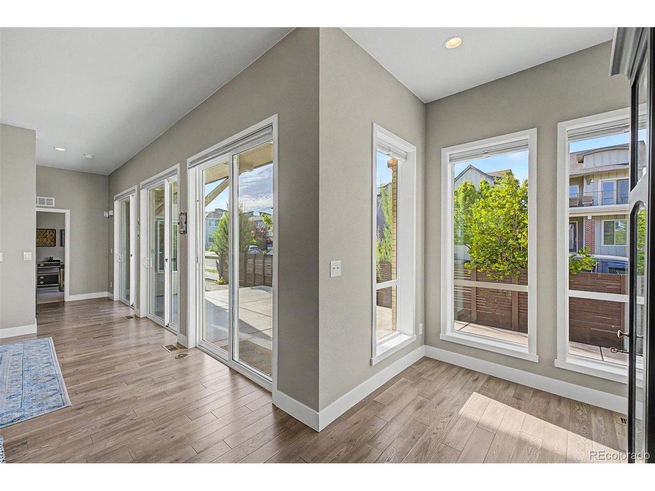 Image 3: Light-filled flex space with vaulted ceilings, wide-plank hardwood floors, and an expansive wall of sliding glass doors opening seamlessly to the outdoor patio - perfect for entertaining or relaxing in the Colorado sunshine.