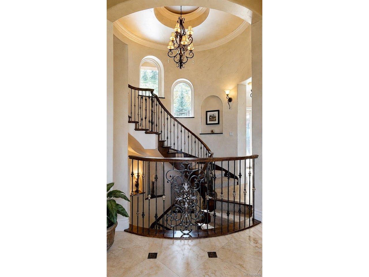 Image 3: A true architectural centerpiece, the home's magnificent self supported spiral staircase with natural lighting from arched windows with custom granite sills gracefully winds through all levels of the residence, creating a dramatic focal point that immediat