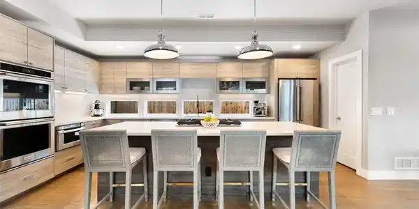 Image 2: The sleek kitchen blends style with practicality, featuring quartz countertops, stainless steel appliances, double ovens, a gas range, overhead lift cabinetry, an eat-in island, and walk-in pantry. Image 2: The sleek kitchen blends style with practicality, featuring quartz countertops, stainless steel appliances, double ovens, a gas range, overhead lift cabinetry, an eat-in island, and walk-in pantry.