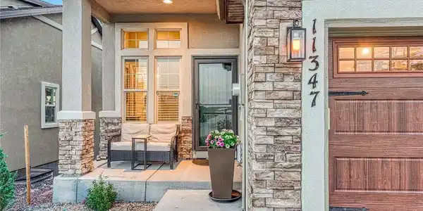 Image 2: A welcoming, south-facing, covered front porch creates the perfect first impression with stone accents and a comfortable space to enjoy the neighborhood surroundings and Pikes Peak views. Image 2: A welcoming, south-facing, covered front porch creates the perfect first impression with stone accents and a comfortable space to enjoy the neighborhood surroundings and Pikes Peak views.
