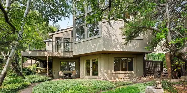 Image 2: Front of the home from the driveway, tucked into mature trees. Image 2: Front of the home from the driveway, tucked into mature trees.