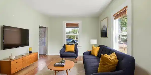 Image 2: Virtually staged living room with pine hardwood flooring throughout, light green wall paint, wooden blinds, and white trim windows. Image 2: Virtually staged living room with pine hardwood flooring throughout, light green wall paint, wooden blinds, and white trim windows.