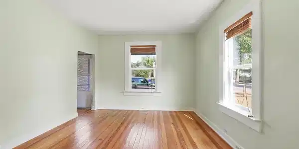 Image 3: Living room with pine hardwood flooring throughout, light green wall paint, wooden blinds, and white trim windows. Image 3: Living room with pine hardwood flooring throughout, light green wall paint, wooden blinds, and white trim windows.