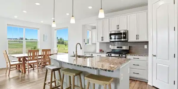 Image 3: Chef-inspired kitchen featuring a large granite island with seating, stainless steel appliances, white cabinetry, and breathtaking Colorado views from every window Image 3: Chef-inspired kitchen featuring a large granite island with seating, stainless steel appliances, white cabinetry, and breathtaking Colorado views from every window