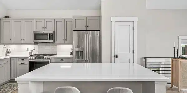 Image 3: Modern kitchen with large white island, stainless steel appliances, and ample counter space Image 3: Modern kitchen with large white island, stainless steel appliances, and ample counter space