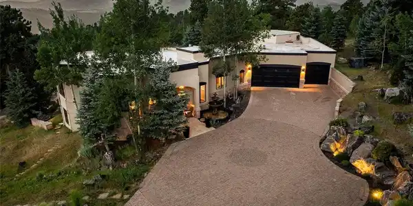 Image 3: Dramatic sunset aerial showcases the home's sweeping circular paver driveway, six-car garage, and outstanding views of the surrounding foothills.