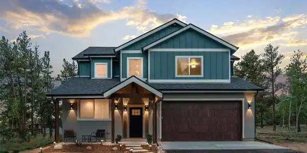 Image 2: Step closer and the details do the talking - landscape lighting winding up the walkway, a covered entry made for morning coffee, and that striking blue-gray board and batten facade glowing against a painted sky. This is the kind of curb appeal that stops y