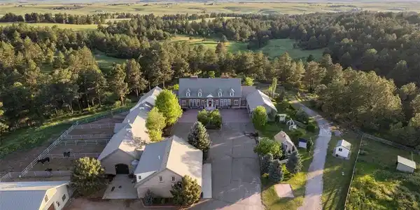 Image 2: Thistle Hill Farm emerges from the pines - residence, barns, and courtyard united in a design as intentional as the 80 acres that surround it.