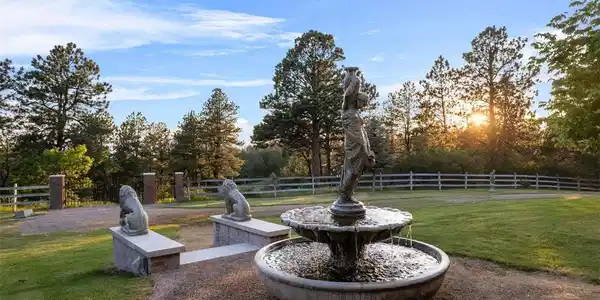 Image 4: Golden hour in the gardens, where a classical fountain and stone lions set the tone for a property that rewards you at every turn of the day.