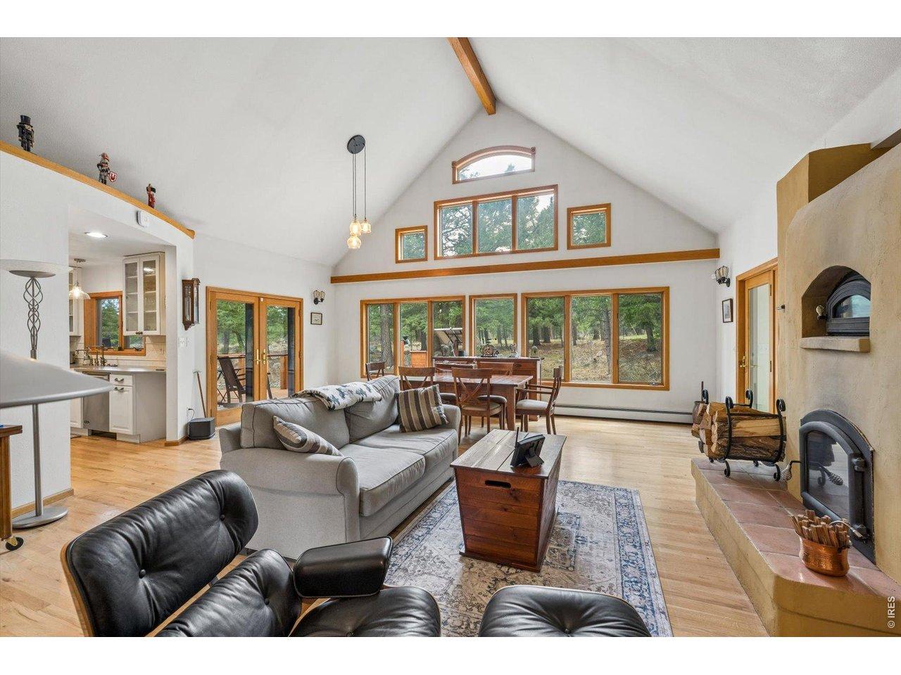 Image 3: Windows on South side of living room, natural wood fireplace with pizza oven above, ceiling fan Image 3: Windows on South side of living room, natural wood fireplace with pizza oven above, ceiling fan