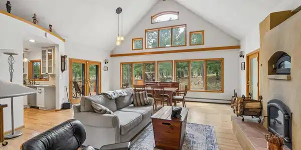 Image 3: Windows on South side of living room, natural wood fireplace with pizza oven above, ceiling fan Image 3: Windows on South side of living room, natural wood fireplace with pizza oven above, ceiling fan