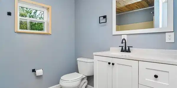 Image 4: Primary bathroom with new tongue and groove ceiling and wall, new vent fan, lighting, and paint.