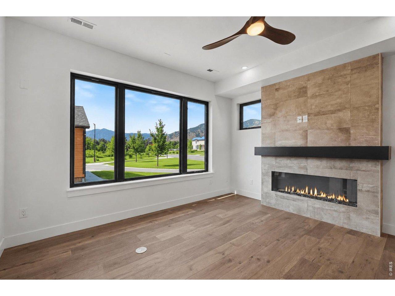 Image 2: Anchored by a sleek electric fireplace with a striking custom tile surround, the sun-filled living room offers the perfect place to relax while enjoying beautiful Flatirons views through expansive south-facing windows.