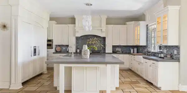 Image 4: The updated kitchen pairs custom cabinetry and poured concrete countertops with an oversized island, generous storage and a large walk-in pantry. Image 4: The updated kitchen pairs custom cabinetry and poured concrete countertops with an oversized island, generous storage and a large walk-in pantry.