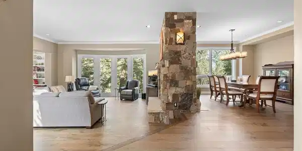 Image 4: The main level unfolds around a dramatic great room anchored by a double-sided stone fireplace