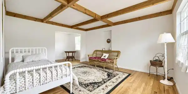 Image 4: Bright living room showcases beautiful wood flooring and distinctive natural wood coffered ceiling beams.