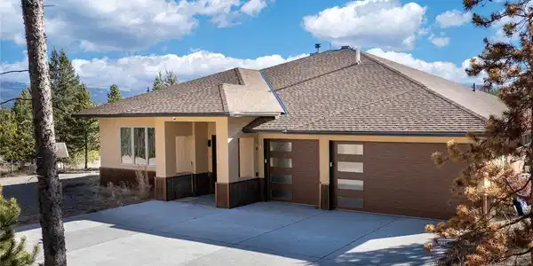 Image 2: Covered front entry with stone and stucco exterior along a paved, county-maintained approach.