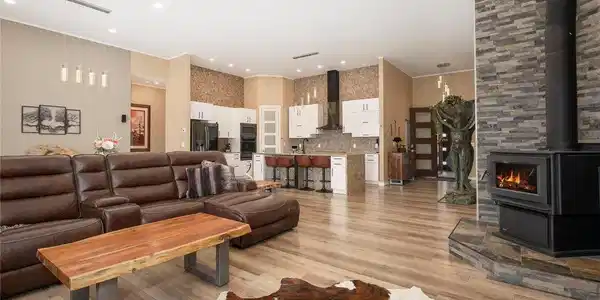 Image 3: Vaulted great room with wood-burning stone fireplace and panoramic mountain-view windows.