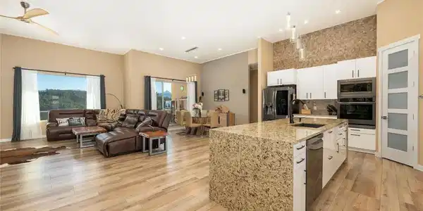 Image 4: Open-concept kitchen island flows into the great room with wide-plank flooring and mountain views.