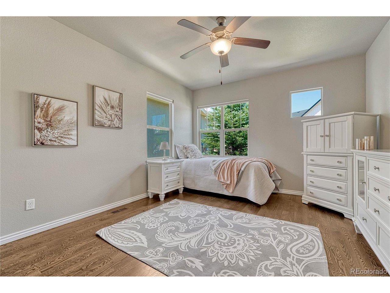 Image 4: The main-level guest bedroom boasts pristine oak hardwood floors and large windows, offering an ideal space for multi-generational living or a highly private home office Image 4: The main-level guest bedroom boasts pristine oak hardwood floors and large windows, offering an ideal space for multi-generational living or a highly private home office