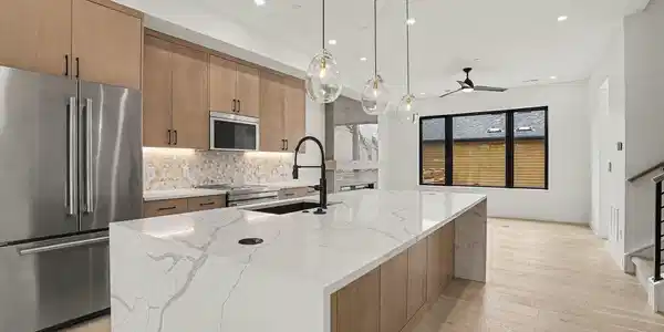 Image 4: At the heart of the home, an oversized waterfall-edge island anchors the open-concept main level, offering generous prep space, storage, and a natural gathering place for entertaining. Image 4: At the heart of the home, an oversized waterfall-edge island anchors the open-concept main level, offering generous prep space, storage, and a natural gathering place for entertaining.