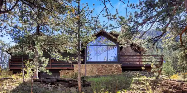Image 4: Dramatic floor-to-ceiling windows, natural wood siding, and generous outdoor living spaces create a striking mountain retreat surrounded by towering pines. Image 4: Dramatic floor-to-ceiling windows, natural wood siding, and generous outdoor living spaces create a striking mountain retreat surrounded by towering pines.
