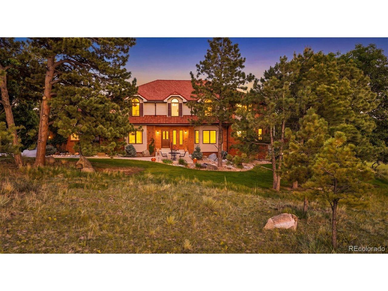 Image 4: The front exterior blends brick, mature pines, lawn, and natural acreage, creating an established Colorado setting with privacy and character. Image 4: The front exterior blends brick, mature pines, lawn, and natural acreage, creating an established Colorado setting with privacy and character.
