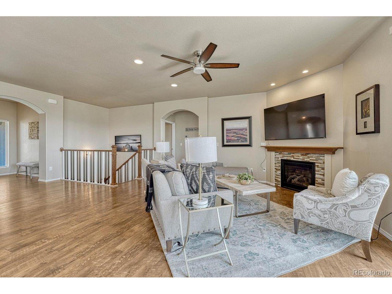 Image 3: The Living Room features LVP flooring, a lighted ceiling fan, and gas fireplace with stone surround. Image 3: The Living Room features LVP flooring, a lighted ceiling fan, and gas fireplace with stone surround.
