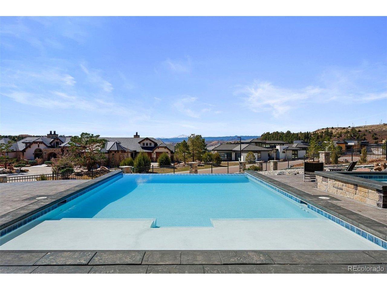 Image 2: Saltwater infinity edge pool with integrated sun shelf, stamped concrete pool deck, and panoramic mountain views.
