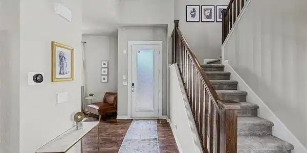 Image 4: Dramatic two-story entry foyer with rich hardwood-style flooring, elegant staircase with dark wood railing, runner rug, and smart home thermostat. Console table and curated art create an inviting first impression. Image 4: Dramatic two-story entry foyer with rich hardwood-style flooring, elegant staircase with dark wood railing, runner rug, and smart home thermostat. Console table and curated art create an inviting first impression.