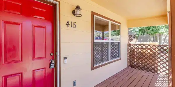 Image 3: Covered porch featuring a red entry door, horizontal siding, and wood-finish decking Image 3: Covered porch featuring a red entry door, horizontal siding, and wood-finish decking
