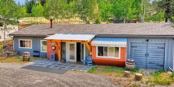 Image 2: A welcoming mountain retreat featuring colorful siding, a rustic timber-framed entrance, and a peaceful setting surrounded by mature trees. Image 2: A welcoming mountain retreat featuring colorful siding, a rustic timber-framed entrance, and a peaceful setting surrounded by mature trees.