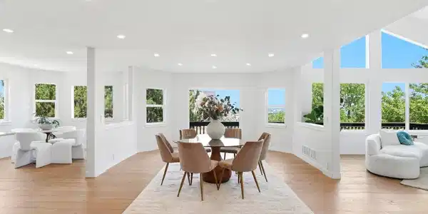 Image 4: Spacious formal dining area surrounded by windows, beautiful wood flooring, and abundant natural light, with open sightlines to the adjoining living spaces. Image 4: Spacious formal dining area surrounded by windows, beautiful wood flooring, and abundant natural light, with open sightlines to the adjoining living spaces.