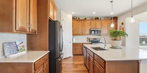 Image 4: This stunning chef's kitchen is designed with an open floor plan that flows seamlessly into the main living spaces. The expansive central kitchen island is beautifully paired with durable, high-end countertops and warm wood cabinetry that offers abundant s