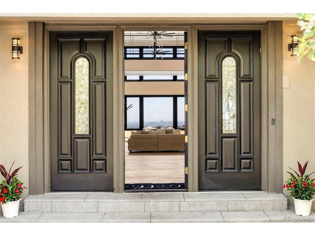 Image 3: The front entry presents arched stained-glass panels frame a sightline that runs straight through the home and out to the Denver skyline. An invitation to experience the luxury inside. Image 3: The front entry presents arched stained-glass panels frame a sightline that runs straight through the home and out to the Denver skyline. An invitation to experience the luxury inside.