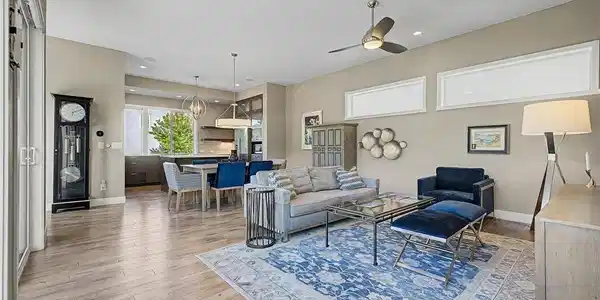 Image 4: Spacious open-concept great room with soaring ceilings, wide-plank hardwood floors, and a cohesive designer color palette. Flows effortlessly into the dining and kitchen areas, anchored by a bold blue area rug and statement ceiling fan. Image 4: Spacious open-concept great room with soaring ceilings, wide-plank hardwood floors, and a cohesive designer color palette. Flows effortlessly into the dining and kitchen areas, anchored by a bold blue area rug and statement ceiling fan.