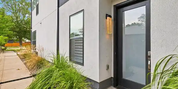 Image 3: Clean-lined architecture, mature ornamental grasses and a covered entry create inviting curb appeal.