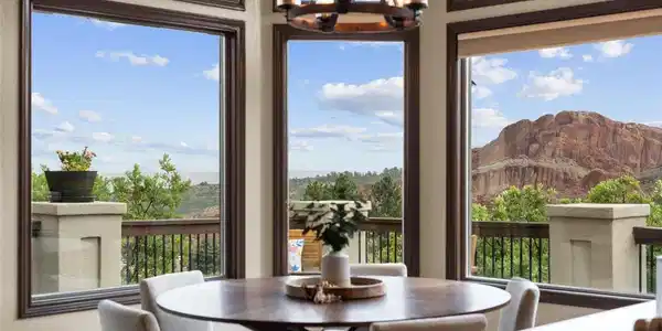 Image 2: Walls of windows frame dramatic red-rock views from the dining area, bringing one of Roxborough Park's most distinctive landscapes directly into the home.
