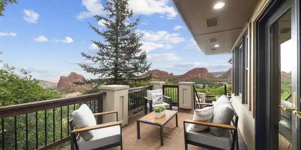 Image 3: Spacious deck offering an inviting outdoor living area surrounded by mature trees and the unmistakable red-rock backdrop of Roxborough.