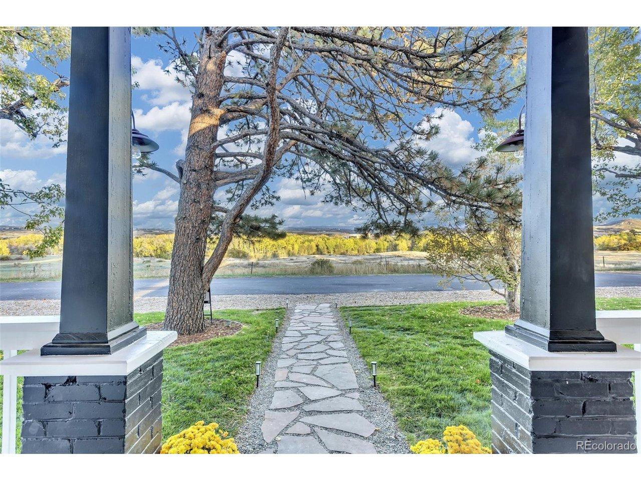 Image 3: Front Porch Views: A dramatic perspective from the porch, showcasing the flagstone path, manicured lawn, and the expansive Colorado vistas beyond. Front porch facing open space
