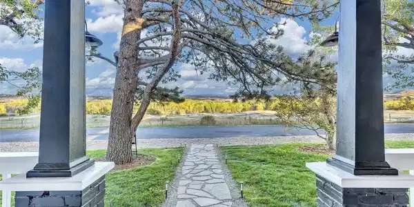 Image 3: Front Porch Views: A dramatic perspective from the porch, showcasing the flagstone path, manicured lawn, and the expansive Colorado vistas beyond. Front porch facing open space Image 3: Front Porch Views: A dramatic perspective from the porch, showcasing the flagstone path, manicured lawn, and the expansive Colorado vistas beyond. Front porch facing open space