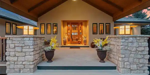 Image 3: A grand entry framed in stone and timber sets the tone before you even step inside - soaring wood-clad ceilings, warm lantern light, and a stately double door flanked by lush potted blooms. It's the kind of threshold that makes coming home feel like an occ Image 3: A grand entry framed in stone and timber sets the tone before you even step inside - soaring wood-clad ceilings, warm lantern light, and a stately double door flanked by lush potted blooms. It's the kind of threshold that makes coming home feel like an occ